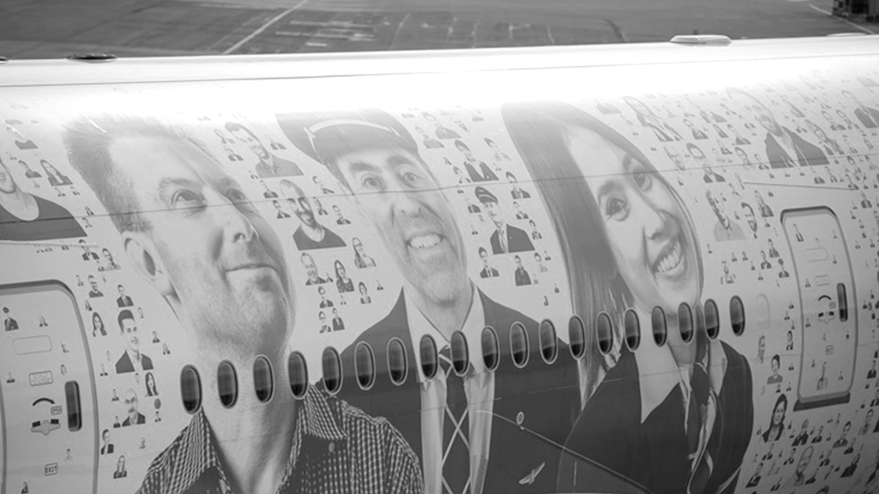 Detail of Swiss International Airlines' Boeing 777-300ER, featuring the iconic “Faces of Swiss” livery, with portraits of over 2,500 employees from various departments, including cabin crew, pilots, technicians, and support staff, symbolizing a culture of recognition and appreciation within the airline.